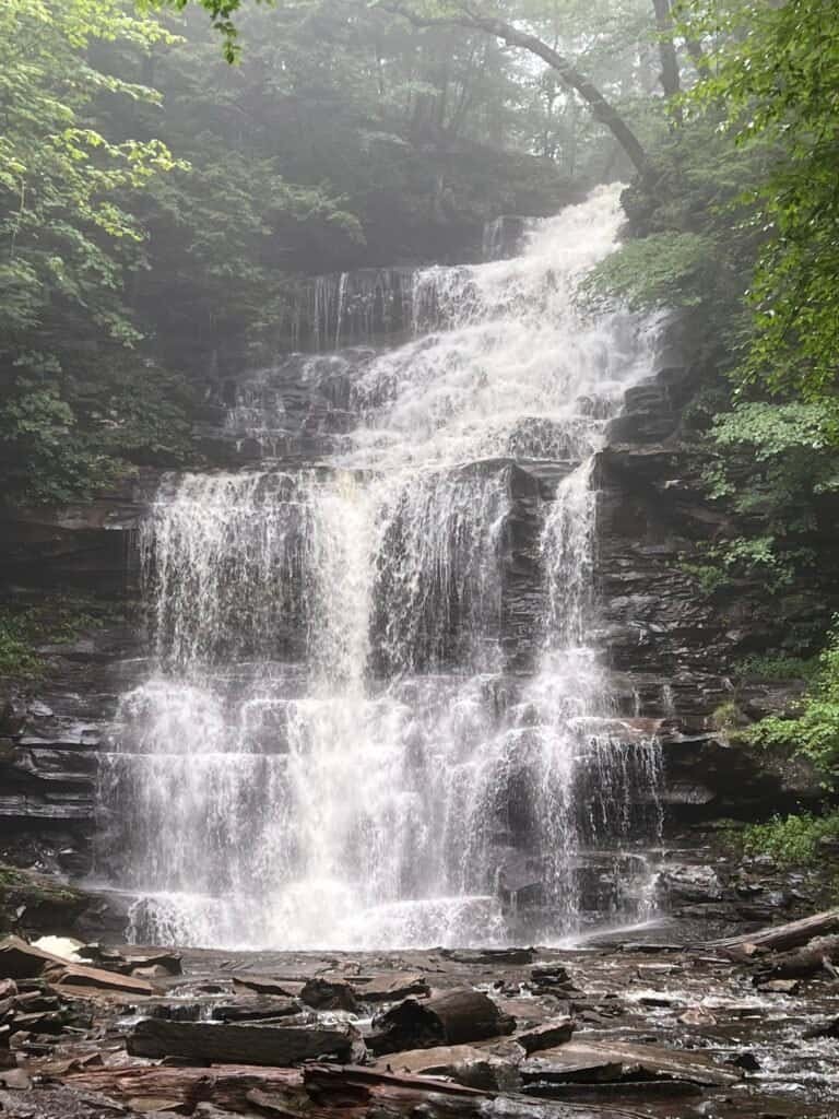 Ganoga Falls cascading down multiple rock tiers in Ricketts Glen State Park, surrounded by dense forest and mist.