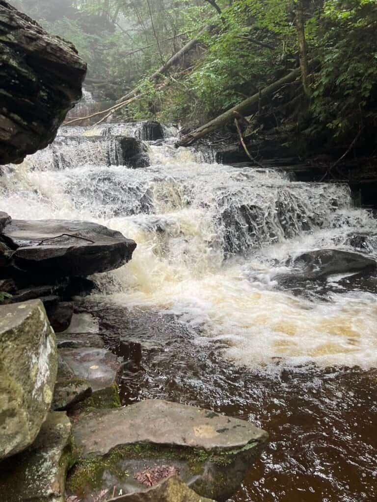 Mohican Falls along the Falls Trail in Ricketts Glen State Park, with water cascading down a series of rocky steps into a narrow stream.
