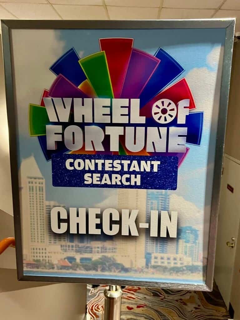 Wheel of Fortune Contestant Search check-in sign displayed inside a venue hallway with colorful show branding.