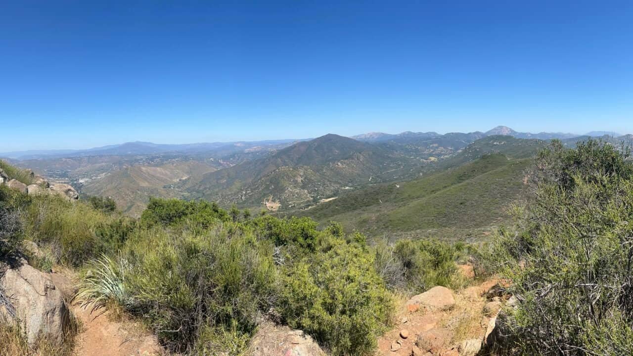 Panoramic view from the summit of McGinty Mountain overlooking rolling hills, rugged canyons, and eastern San Diego County under a clear blue sky.