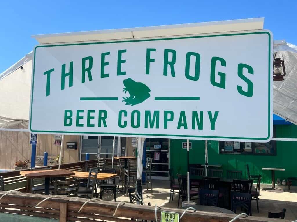 Exterior sign for Three Frogs Beer Company with outdoor seating in Vista, California.