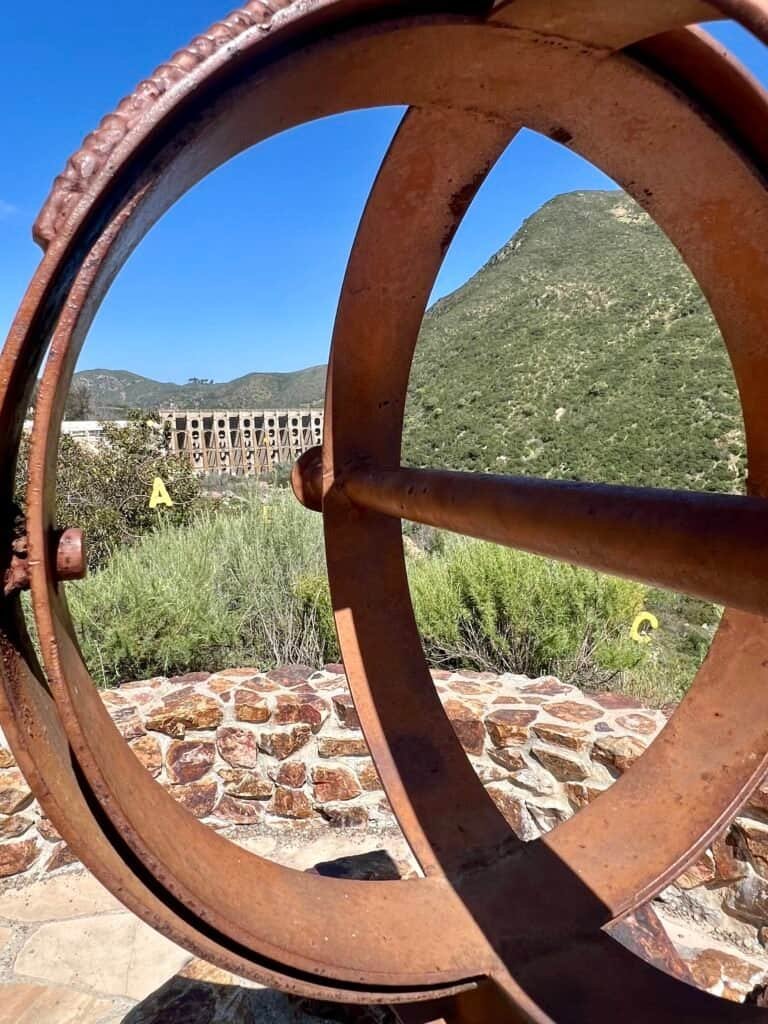 View of Lake Hodges Dam framed through the circular metal pipe scope at Rattlesnake Viewpoint.