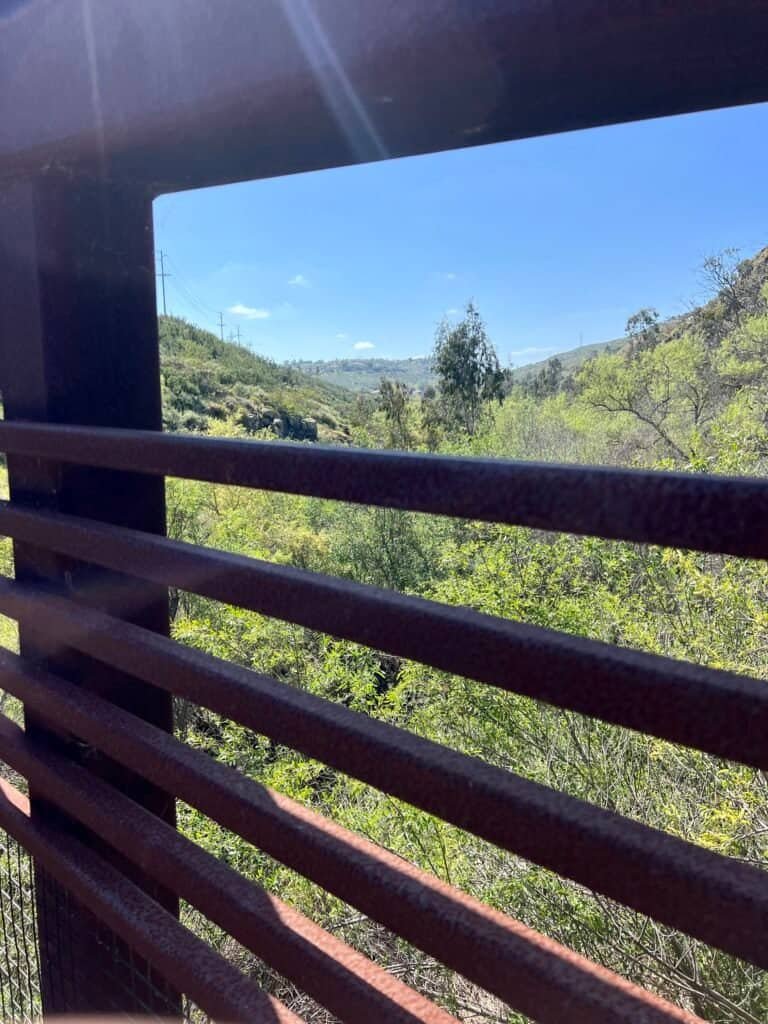 View from Del Dios Bridge looking out over the canyon and surrounding hills through the metal railing