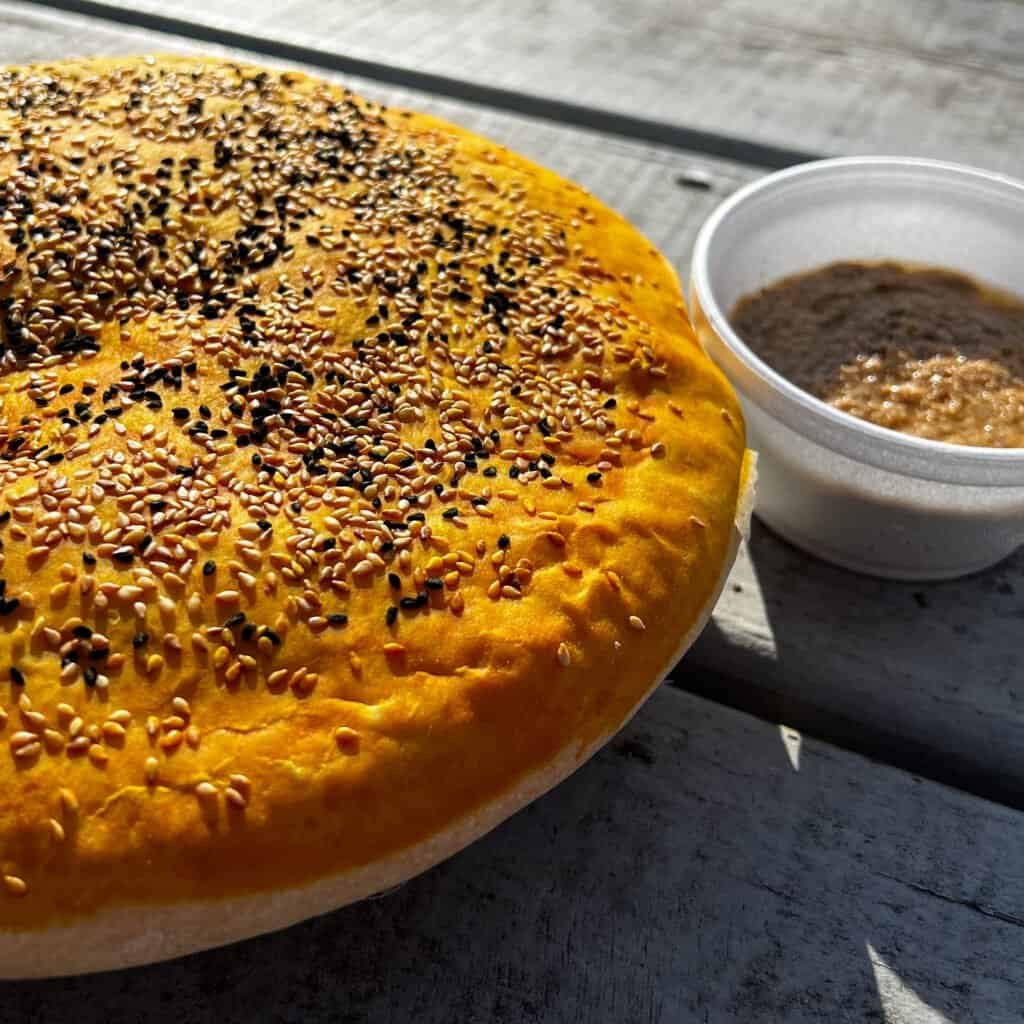 Freshly baked Persian sun bread topped with sesame and nigella seeds served with baba ganoush at the Lexington farmers market.