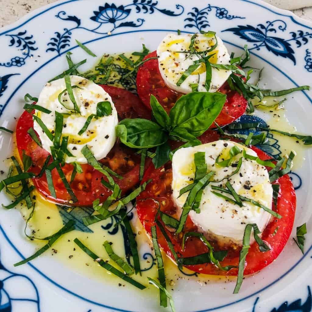 Caprese salad with sliced heirloom tomatoes, fresh mozzarella, basil, and olive oil