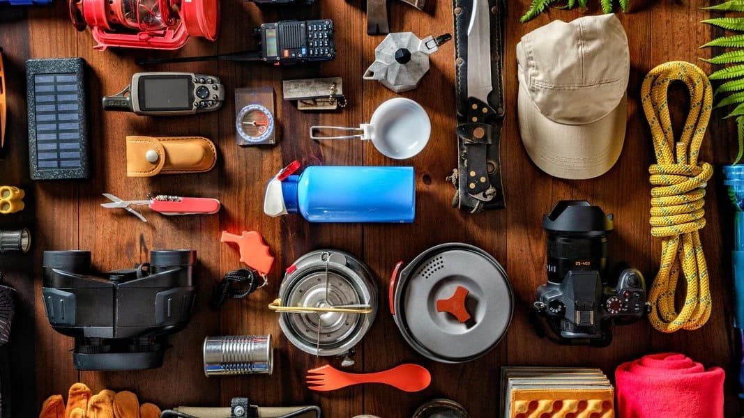 Flat lay of essential day hiking gear including navigation tools, water bottle, first aid items, and safety equipment