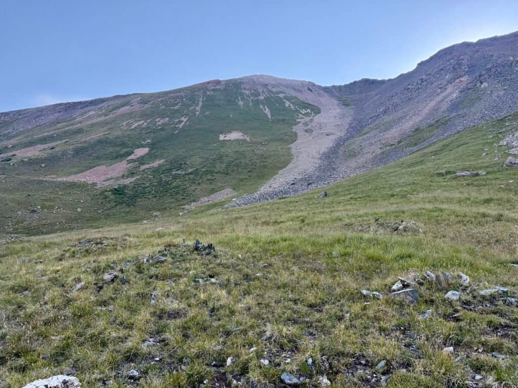 Wide alpine slope and rocky ridgeline above treeline on the Wheeler Peak trail, showing the climb ahead toward the summit.