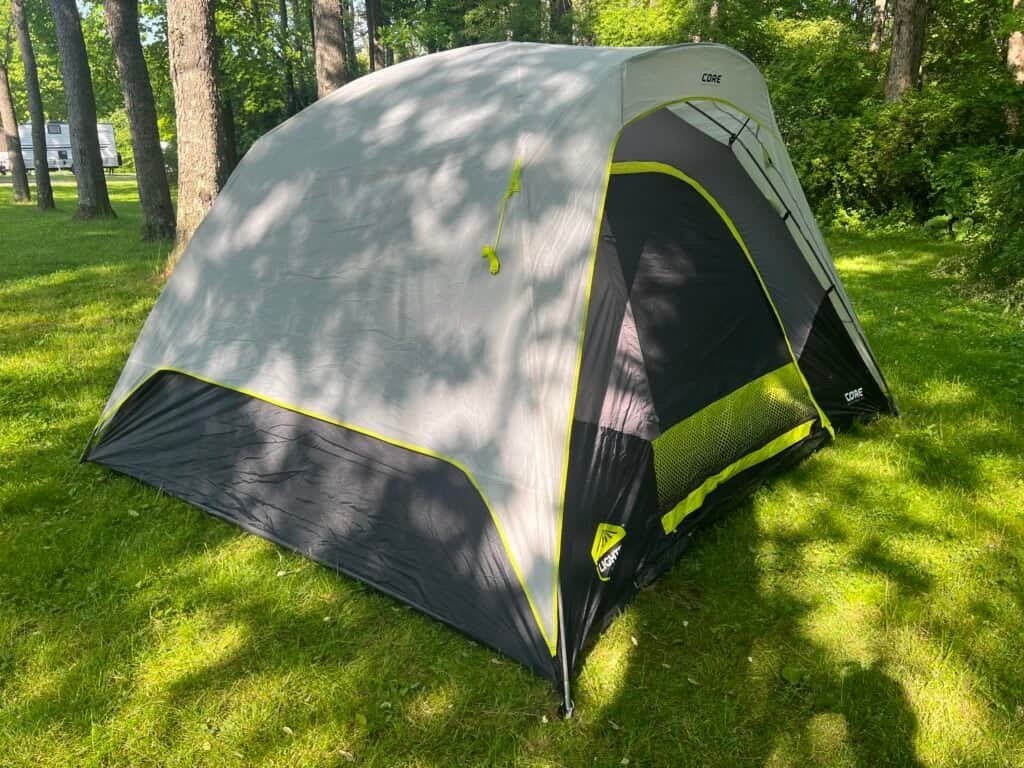 Tent set up at Wolfie’s Campground surrounded by trees on a sunny afternoon