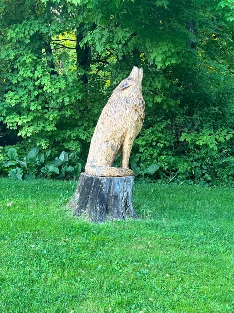 Carved wooden wolf statue on a tree stump at Wolfie’s Campground