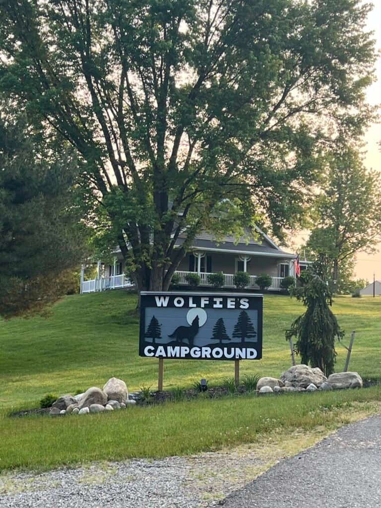 Wolfie’s Campground entrance sign with trees and lodge building in the background