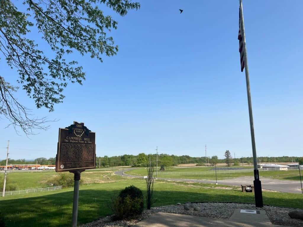 Wide view of Campbell Hill with the Ohio Historical Marker, flagpole, and surrounding landscape on the Ohio Hi-Point Career Center grounds