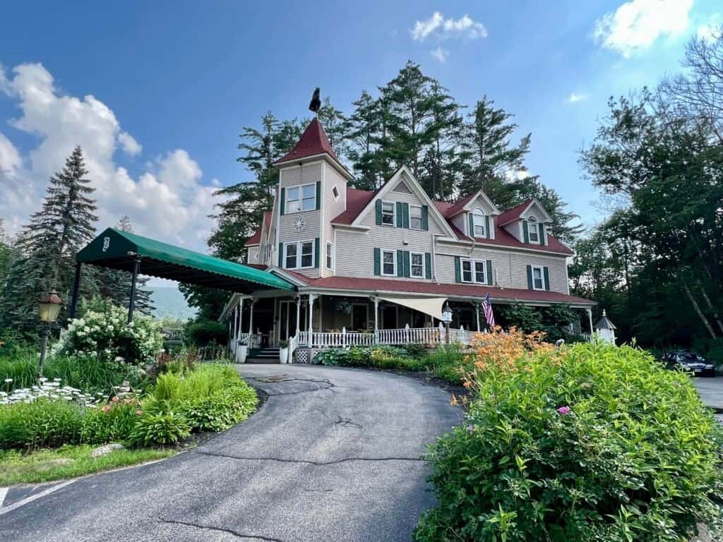 Exterior view of the Bernerhof Inn in Glen, New Hampshire, a historic Victorian-style bed and breakfast with gardens and a wraparound porch.