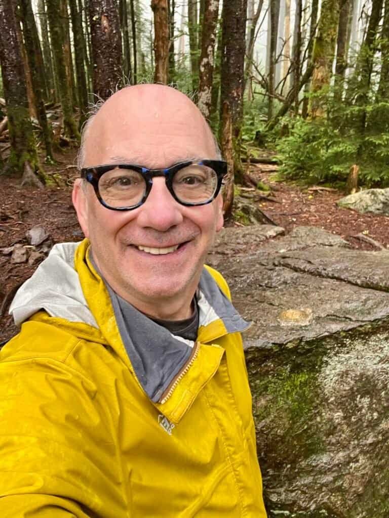 Hiker smiling at the summit of Mount Rogers after a wet and muddy climb