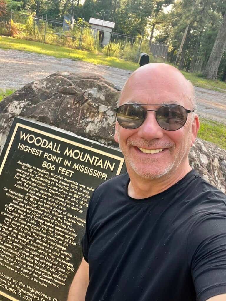 Summit selfie at Woodall Mountain beside the highest point marker in Mississippi