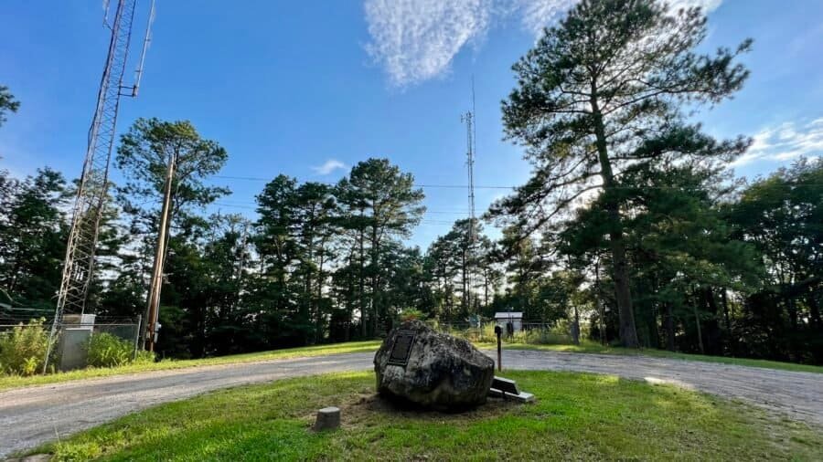 Woodall Mountain summit with plaque, boulder, and radio towers in Mississippi