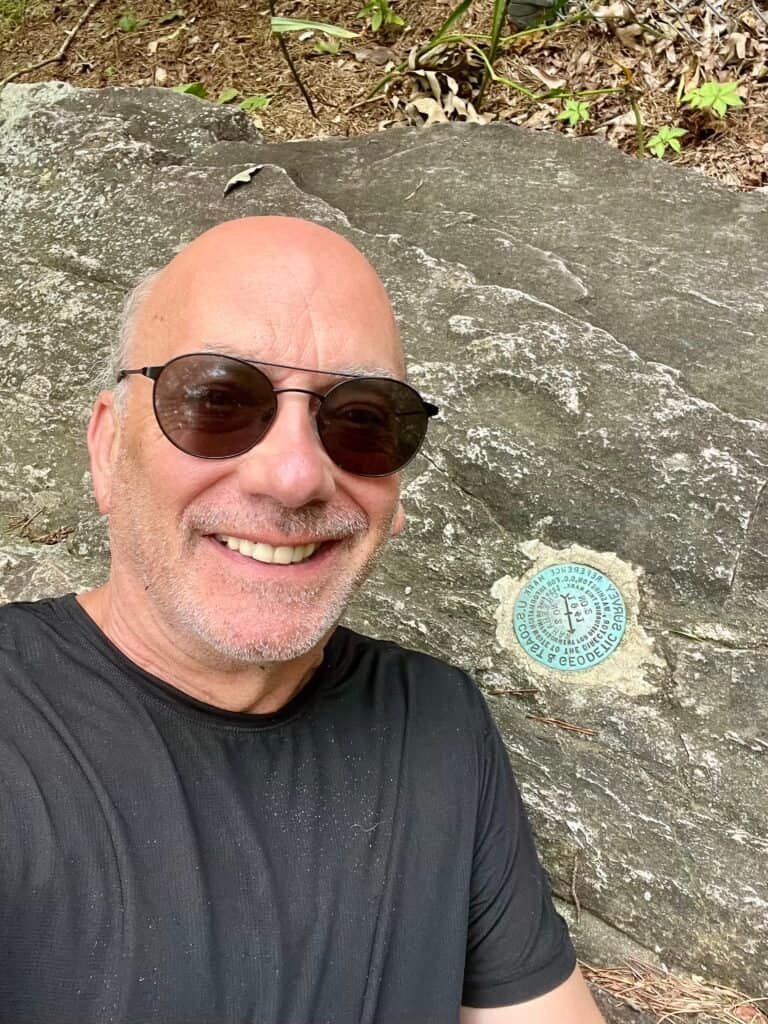 Author selfie beside the official high point survey marker at Cheaha Mountain in Alabama.