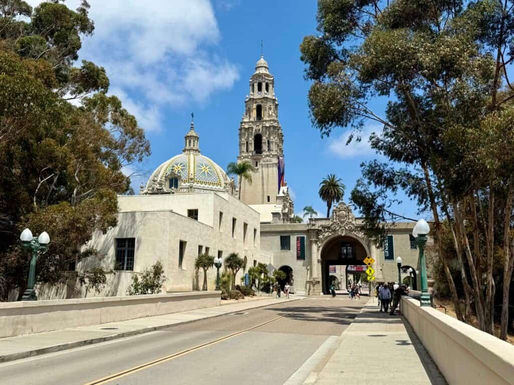 California Tower and tiled dome at Balboa Park framed by trees under a blue San Diego sky