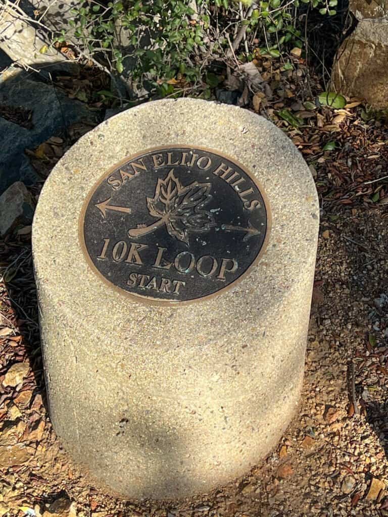 A stone medallion on the ground indicating the start of a 10K loop trail at San Elijo Hills.