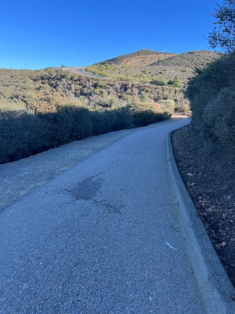 Paved trail section near Double Peak Drive in San Marcos, California, with chaparral-covered hills and clear blue skies