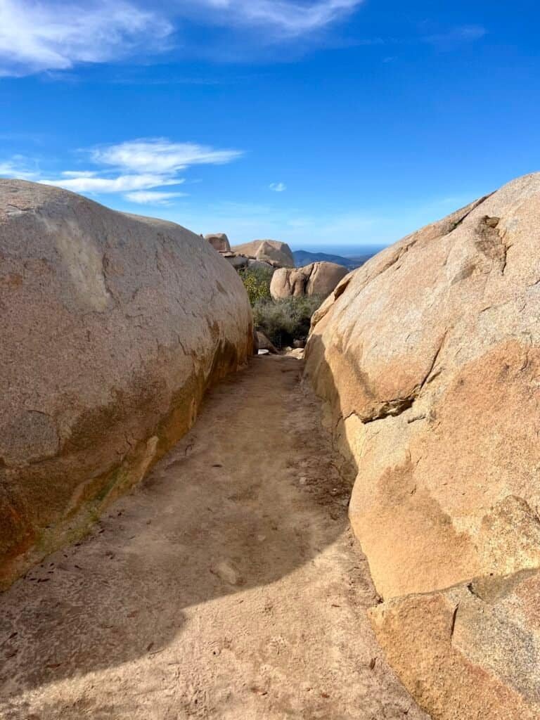 Narrow trail passing between large granite boulders on the Mount Woodson Trail