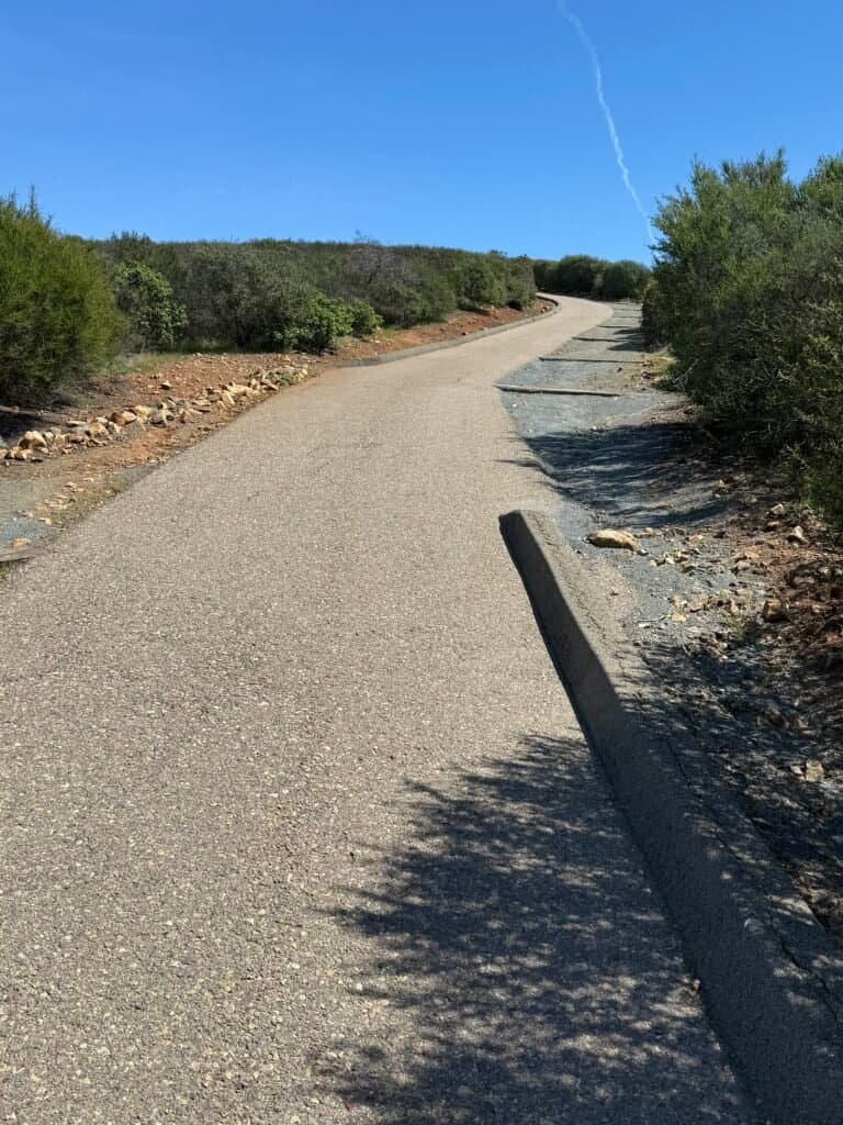 Paved trail climbing toward Lake San Marcos Peak with coastal foothills in the distance