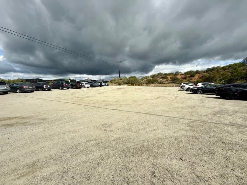 Gravel parking lot at El Cajon Mountain trailhead under dark, stormy clouds in Lakeside, California
