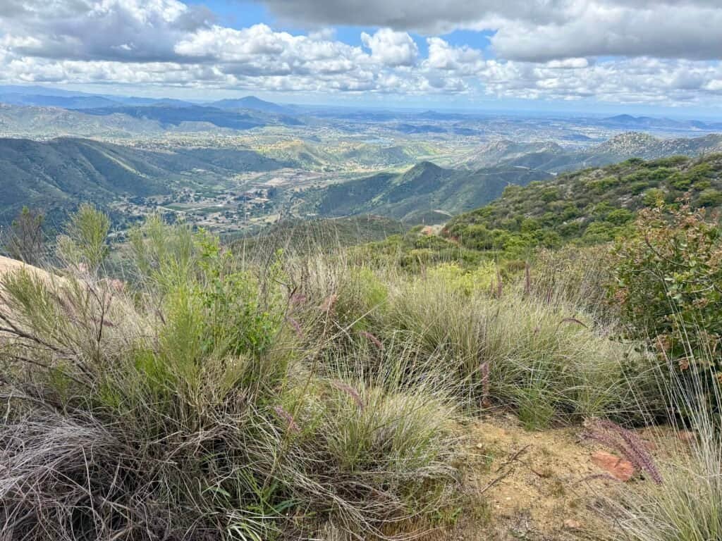 Wide valley views from El Cajon Mountain with rolling green hills and layered mountain ridgelines below.