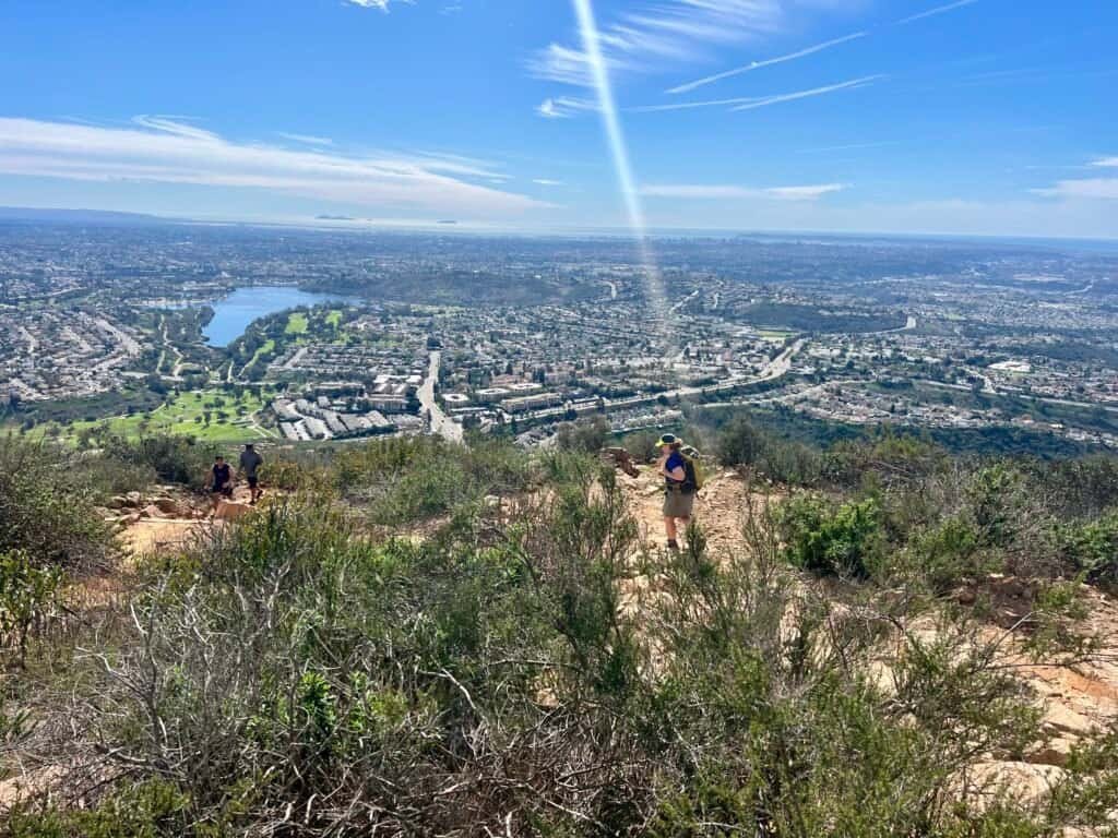 Hiker descending Cowles Mountain with views of Lake Murray and San Diego below