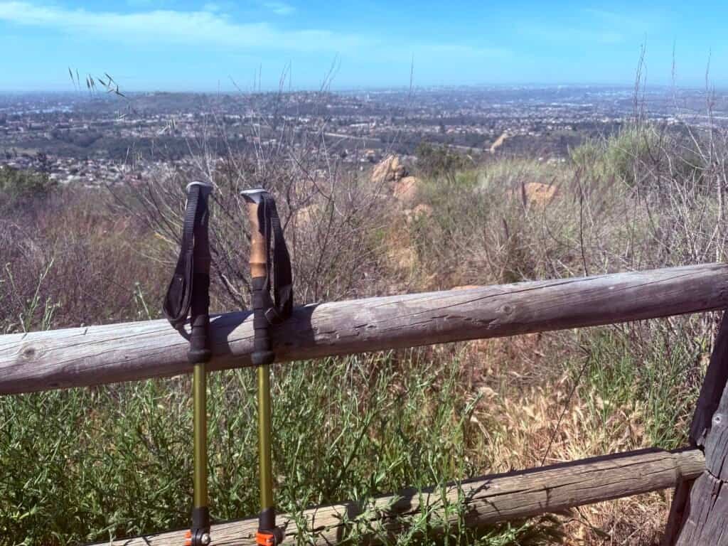 Trekking poles resting on a wooden fence with a view across San Diego from Mission Trails Regional Park.