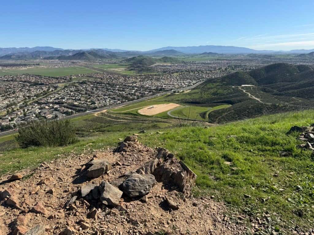 Looking back toward the valley and trail system below from the third summit, with the parking lot visible near the road
