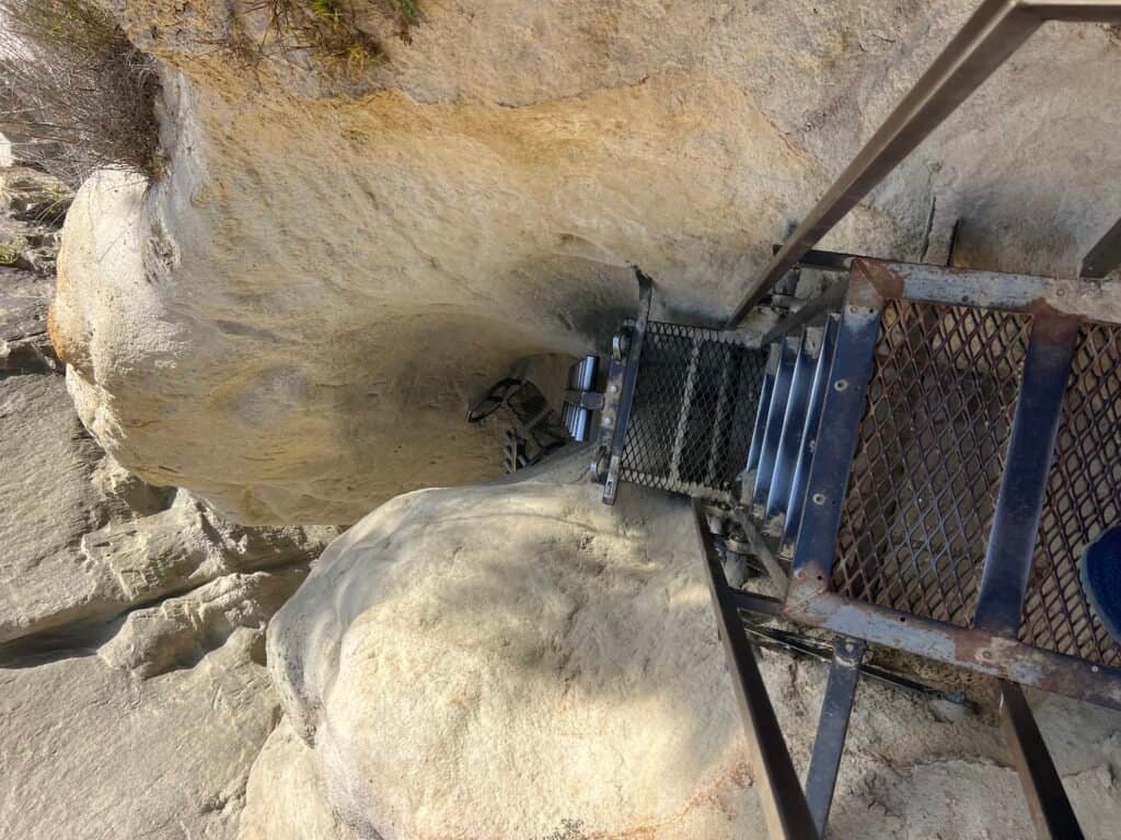 Cave exploration with a metal staircase leading into a rocky underground space.