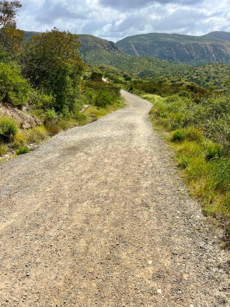 Wide dirt trail descending toward distant Fortuna summits in Mission Trails Regional Park