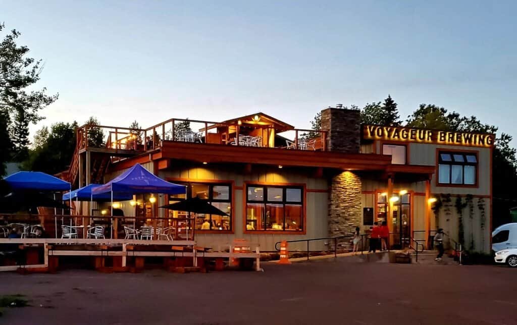 Exterior of Voyageur Brewing Company in Grand Marais at dusk with outdoor seating and rooftop deck.