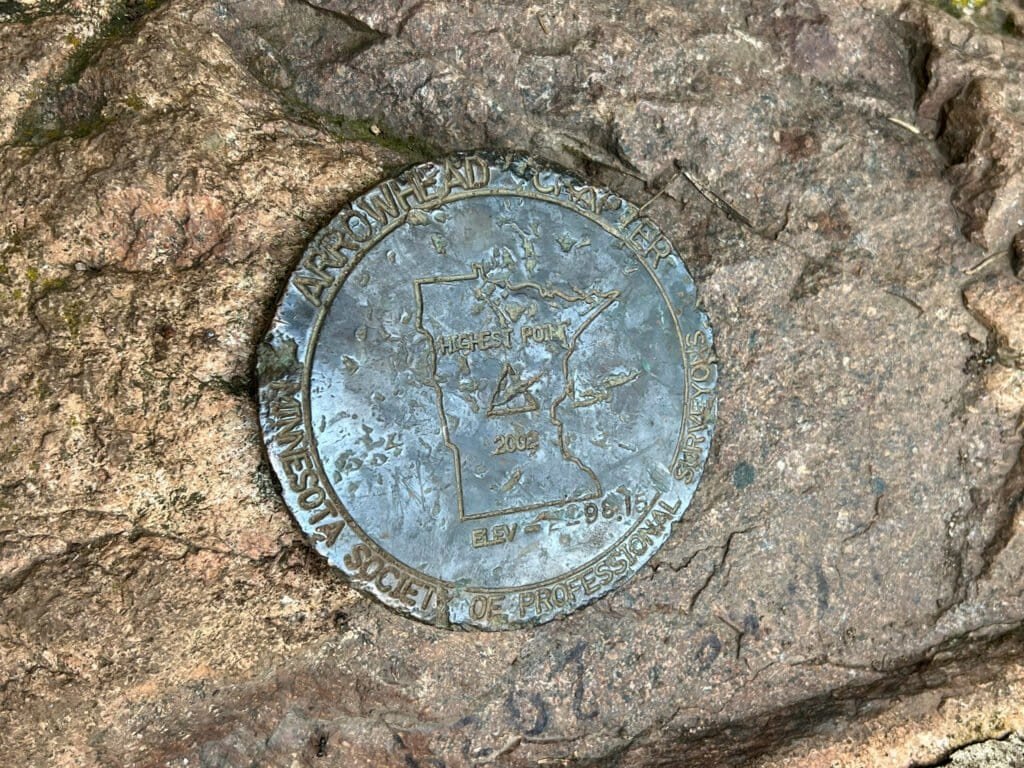 Metal geomarker embedded in rock marking Eagle Mountain as Minnesota’s highest point