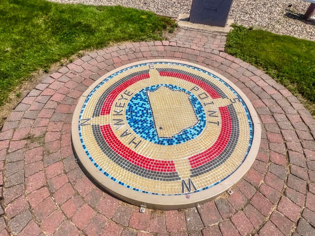 Circular mosaic at Hawkeye Point marking Iowa’s highest elevation with state outline and directional compass design.