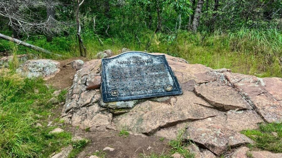 Eagle Mountain summit plaque mounted on a rock outcrop, marking Minnesota’s highest natural point within the Boundary Waters forest.