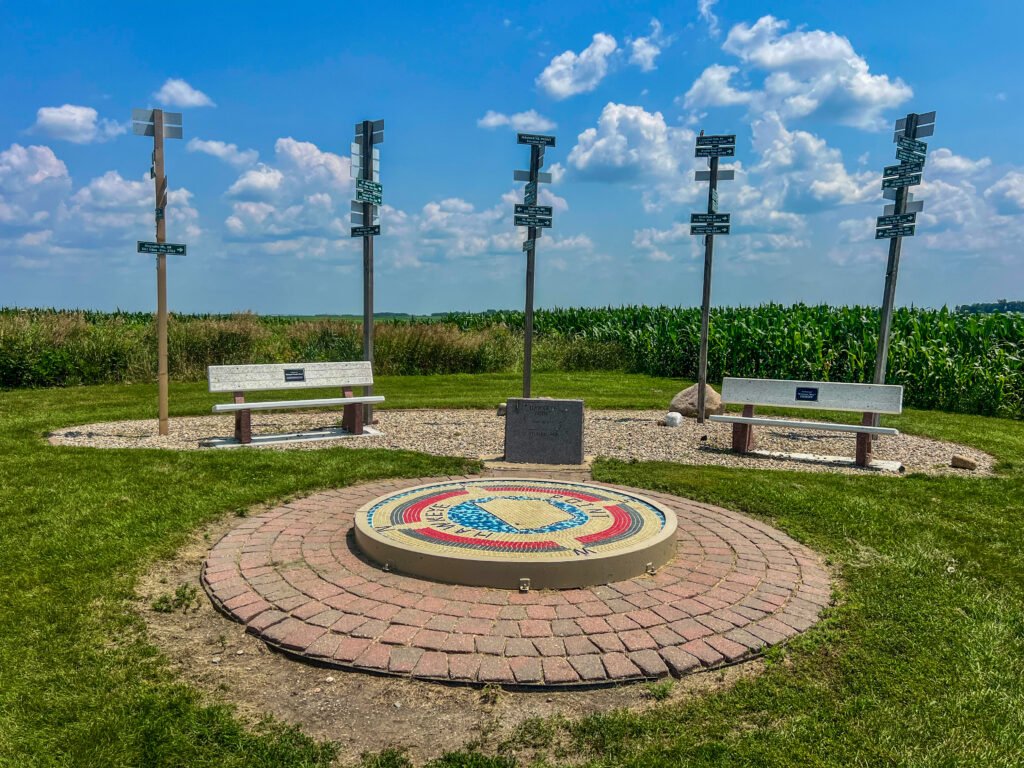 Directional signposts at Hawkeye Point pointing toward the other 49 U.S. state high points with cornfields in the background.