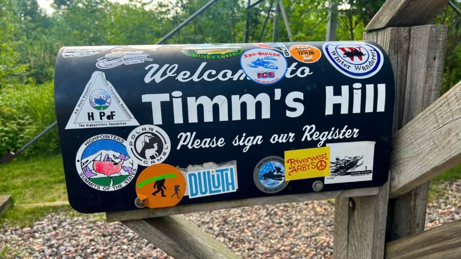 Summit register mailbox at Timms Hill in Wisconsin covered in Highpointers stickers and welcome sign.
