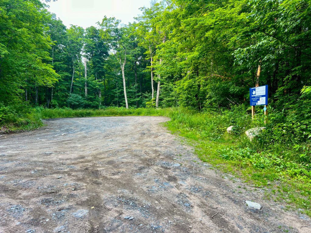 Alt Text (Parking Lot): Small dirt parking lot at Mount Arvon trailhead surrounded by dense Upper Peninsula forest.