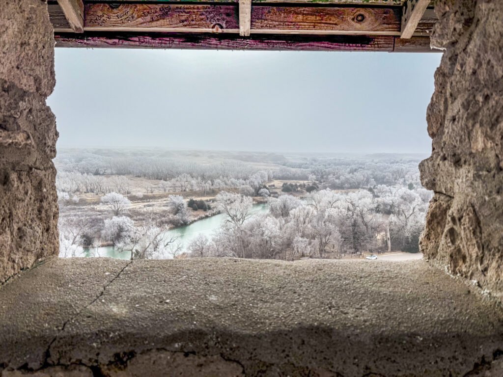 View of Lake Scott and the surrounding frosted valley from inside the stone building on the bluff at Historic Lake Scott State Park.