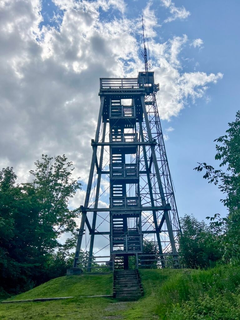 Fire tower at the summit of Timms Hill in Wisconsin against a partly cloudy sky.