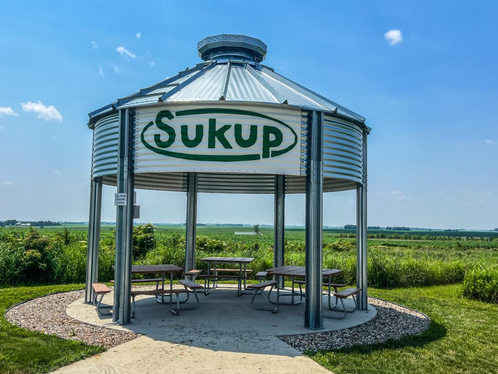 Metal silo-style picnic shelter with tables at Hawkeye Point overlooking Iowa farmland and cornfields.