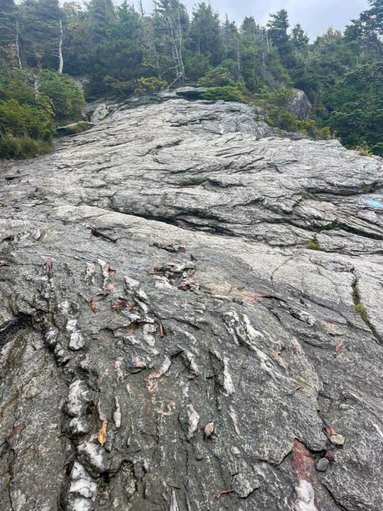 Steep, exposed granite slab on the Sunset Ridge Trail requiring careful footing in wet conditions.