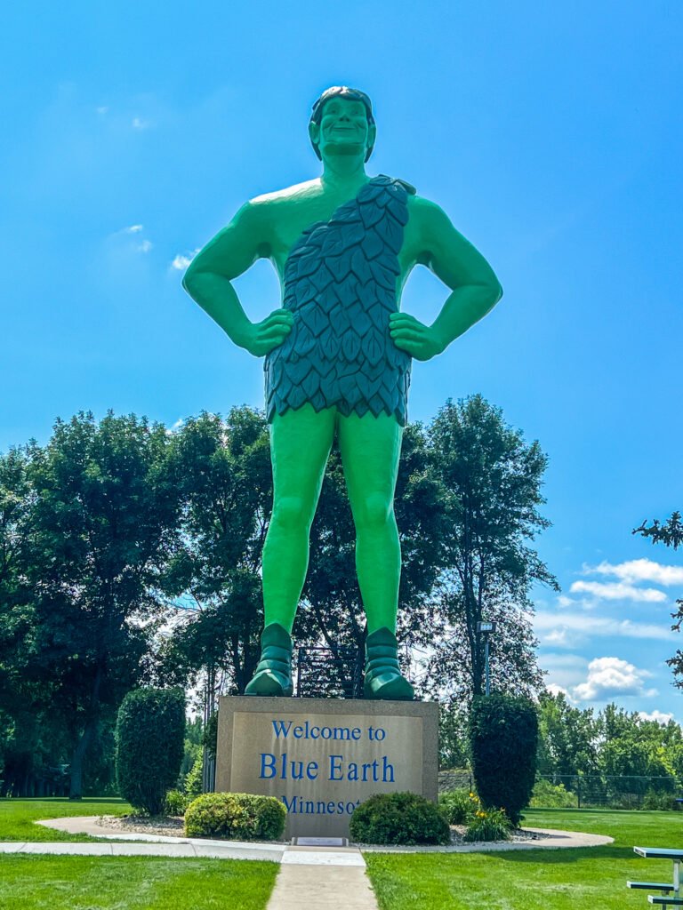 55-foot-tall Jolly Green Giant statue in Blue Earth, Minnesota standing above a welcome sign under a bright blue sky.