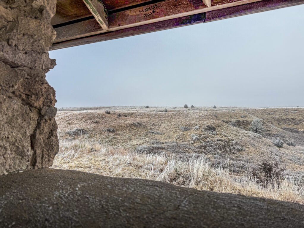 Frost-covered prairie hills viewed from inside the stone bluff-top building at Historic Lake Scott State Park in Kansas.
