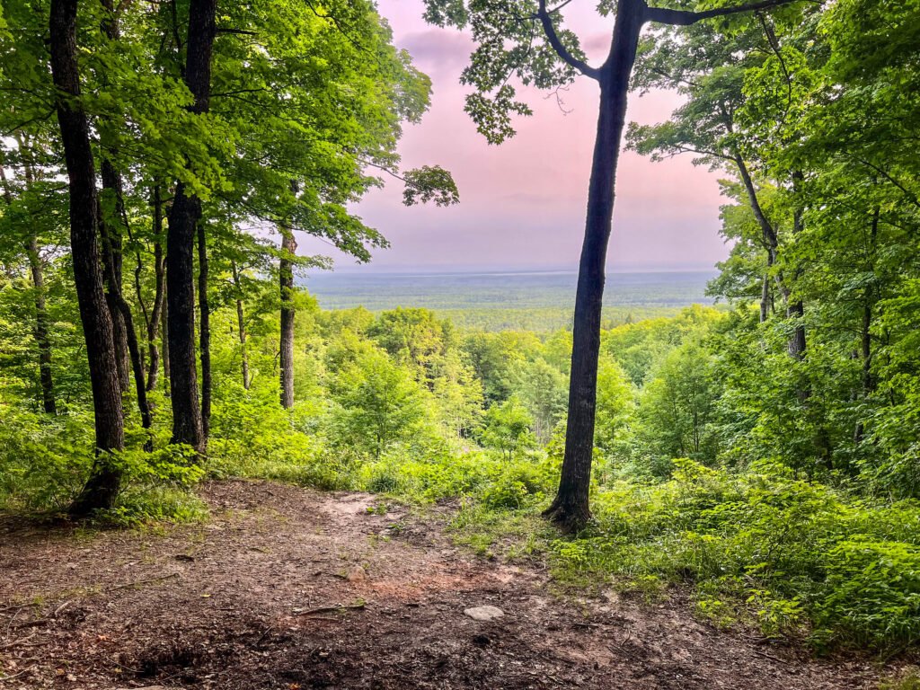 Hazy morning view from the Mount Arvon overlook showing dense Upper Peninsula forest stretching to the horizon.