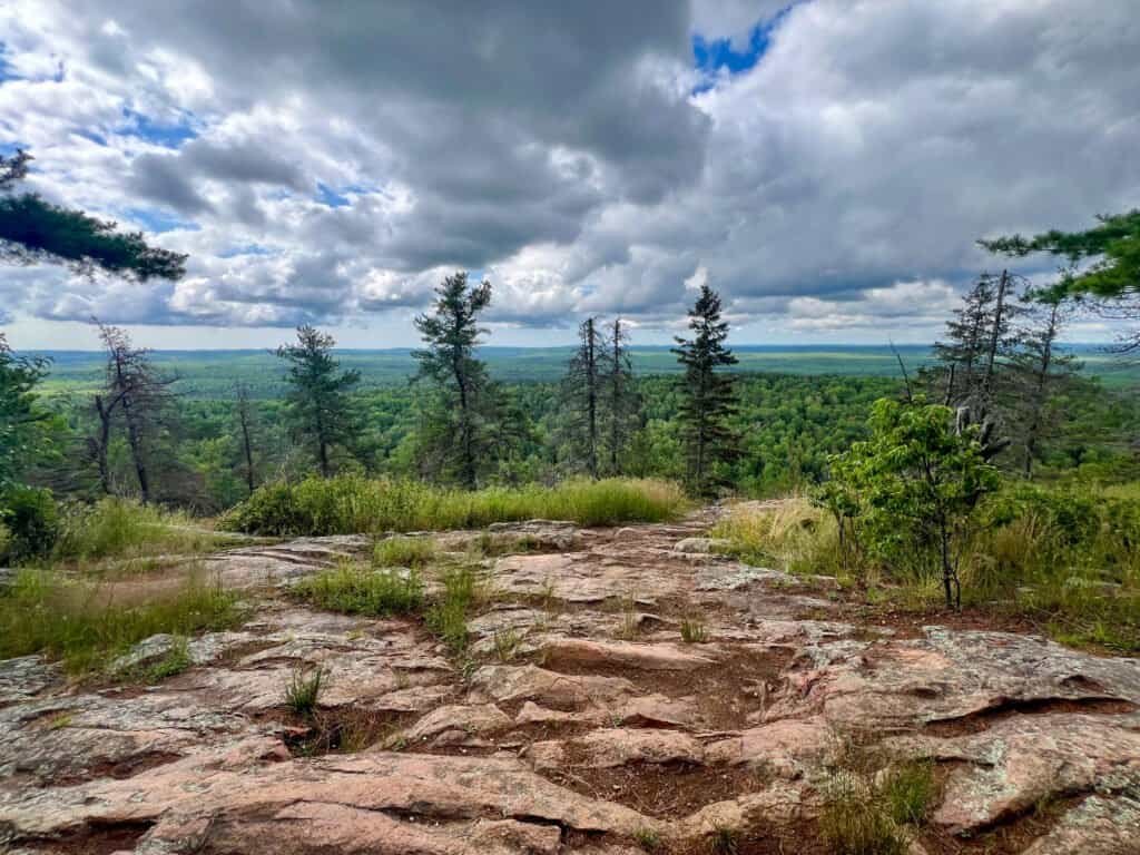First scenic overlook along the Eagle Mountain trail at mile 3.1, overlooking forested landscape under dramatic clouds.