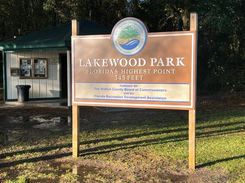 Lakewood Park sign in Walton County, Florida with restrooms visible behind the entrance area.