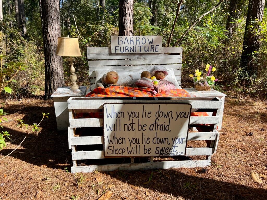 Scarecrow display on a bed with fall decor at Scarecrows in the Park in Opp, Alabama