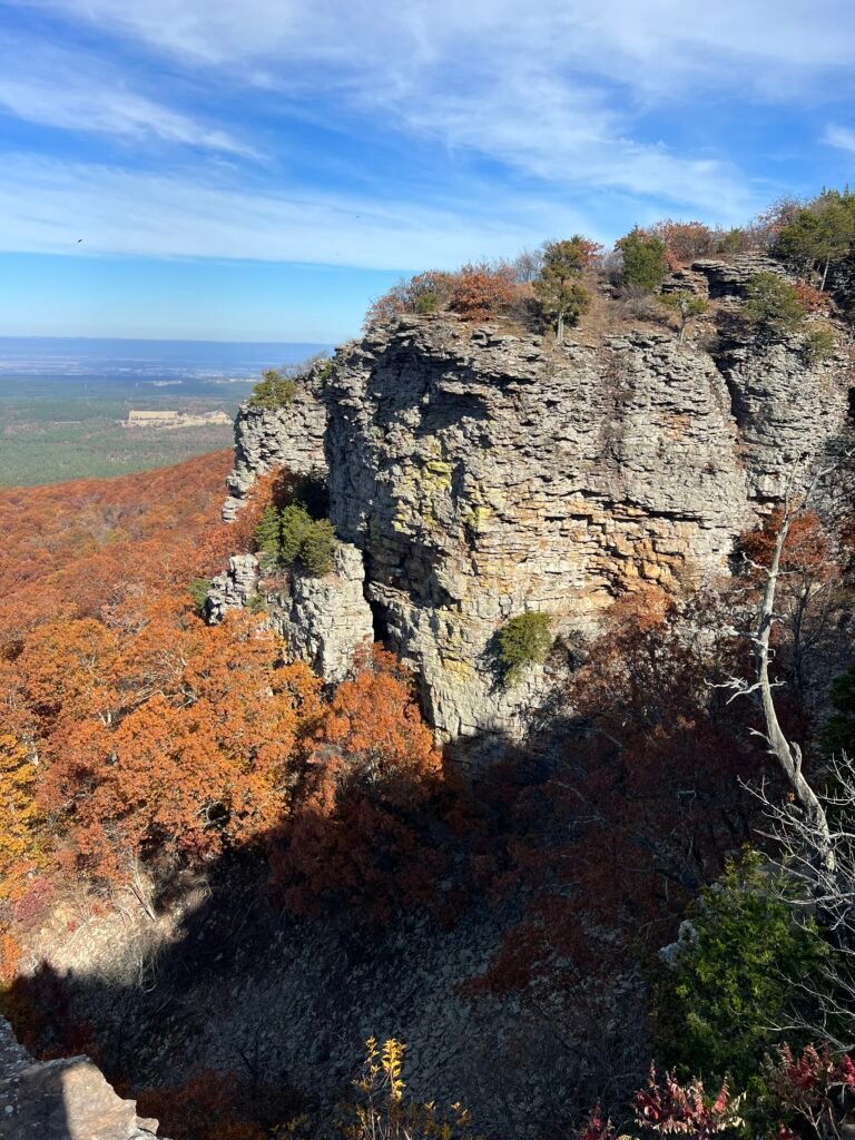 Sheer rock cliffs rise above a forest of autumn colors at Mount Magazine State Park.